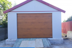garáž sedlová střecha světle šedá omítka sekční vrata zlatý dub
